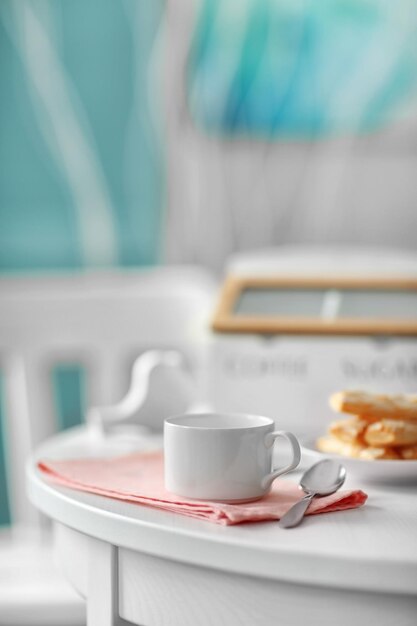 Taza de café con galletas en mesa blanca en interior claro