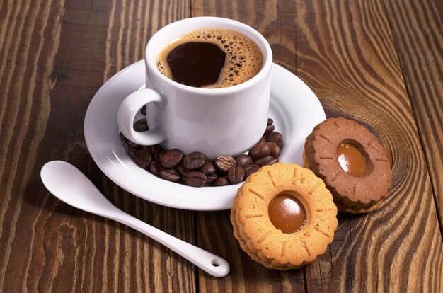 Taza de café con galletas en la mesa de madera de cerca