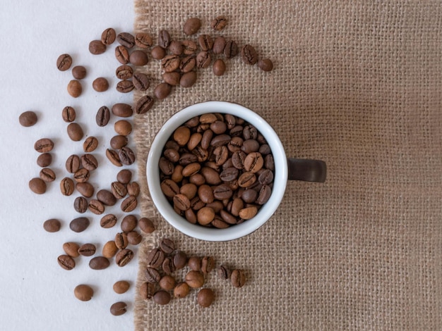 Taza de café y grano en la tela de lona desde arriba.