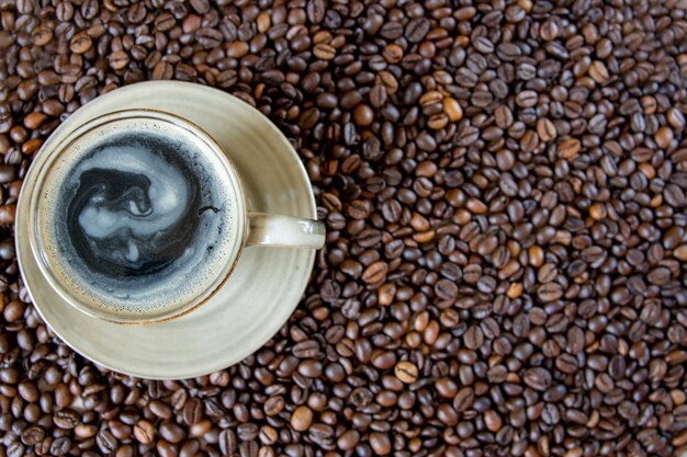 Taza con café en los granos de café asados