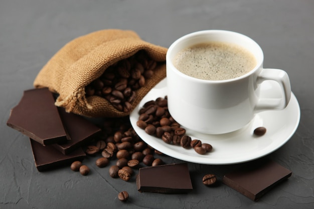 Taza de café, granos de café y chocolate en la mesa de cerca