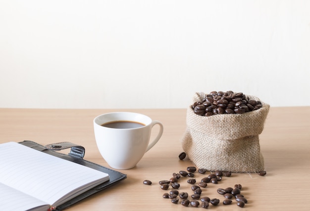 Taza de café con granos de café colocados en una mesa de madera