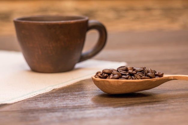 Taza de café y granos de café en cuchara de madera