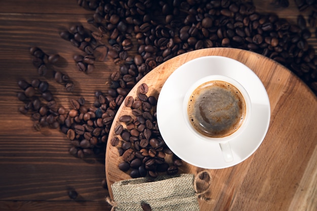 Taza de café con granos de café en el fondo de madera