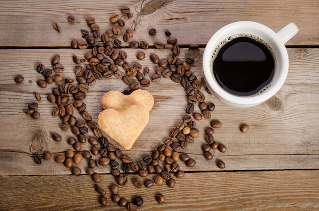 Taza de café, granos de café y galletas-corazones