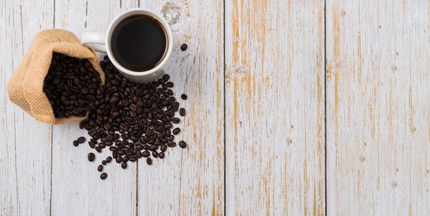 Taza de café y granos de café en la mesa de madera