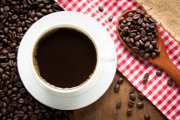 Taza de café y granos de café en la mesa de madera