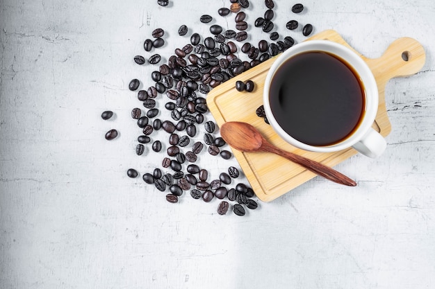 Una taza de café y granos de café sobre un fondo blanco.