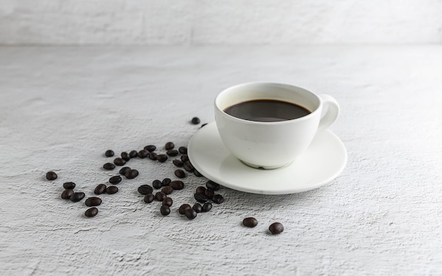 Taza de café con granos de café sobre fondo blanco.