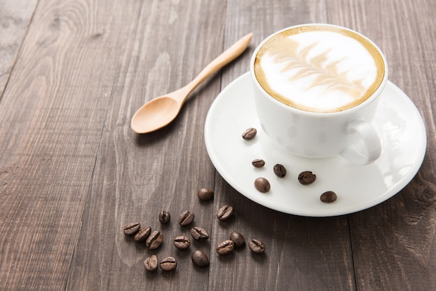 Taza de café y granos de café sobre fondo de madera.