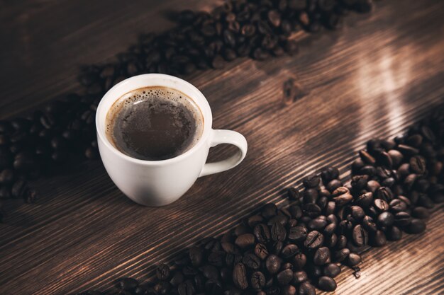 Taza de café y granos de café sobre fondo de madera.