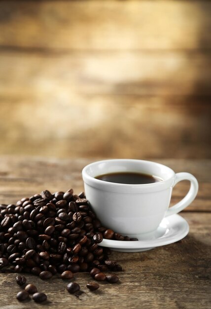 Taza de café y granos de café sobre fondo de madera