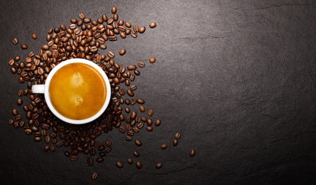 Taza de café y granos de café sobre fondo negro