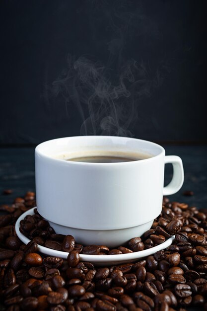 Taza de café con granos de café sobre fondo oscuro