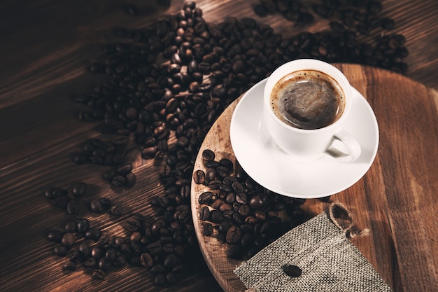 Taza de café y granos de café sobre fondo de tela de saco.