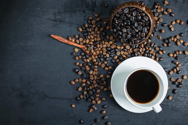 Taza de café y granos de café tostados sobre un fondo negro