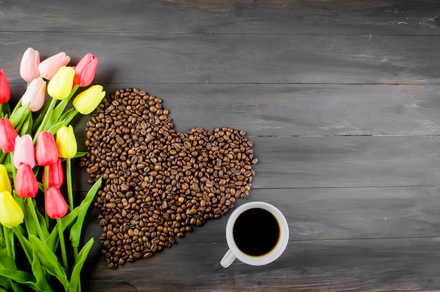 Taza de café, granos de café y tulipanes.