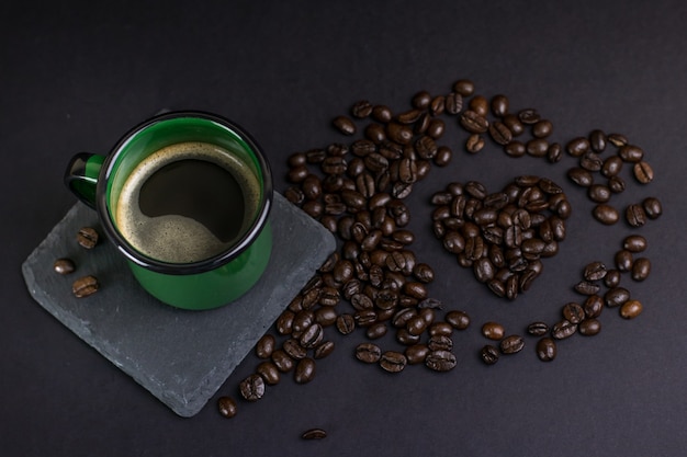 Taza de café con granos de corazón en un fondo oscuro