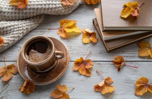 Una taza de café y hojas de otoño en el alféizar de la ventana