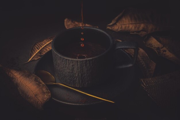 Foto taza de café y hojas de otoño en un fondo oscuro de tono vintage