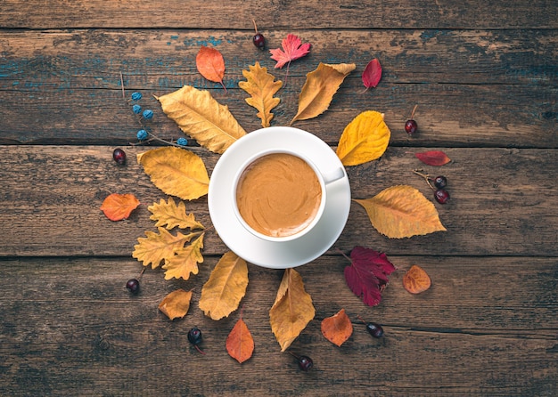 Una taza de café y hojas de otoño sobre un fondo de madera