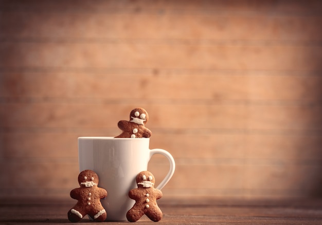 Taza de café con hombre de jengibre en mesa de madera