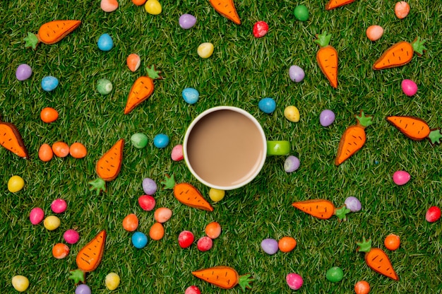 Taza de café y huevos de chocolate de Pascua con zanahorias cookie sobre hierba verde