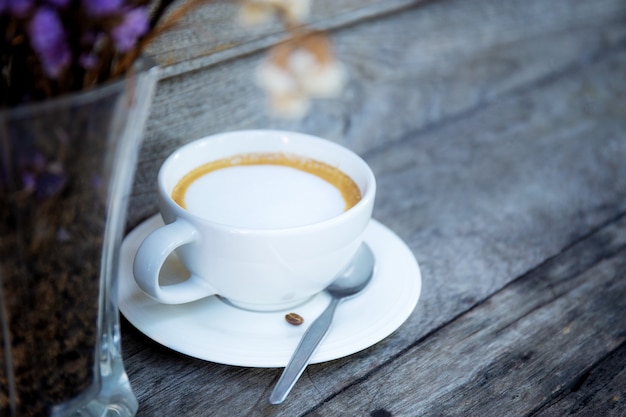 Taza de café y jarrón sobre mesa de madera