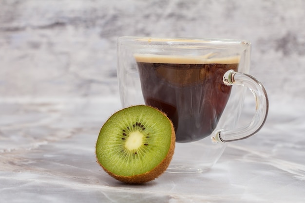 Taza de café y un kiwi en la mesa de la cocina.