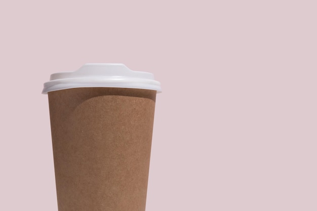 Taza de café kraft para llevar en blanco aislada sobre fondo rosa
