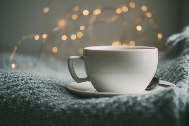 Taza de café con leche en una acogedora manta de invierno tejida