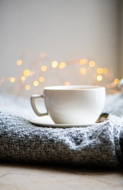 Taza de café con leche en una acogedora manta de invierno tejida