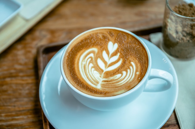 Foto taza de café con leche con aroma de café en la mesa de madera estilo café