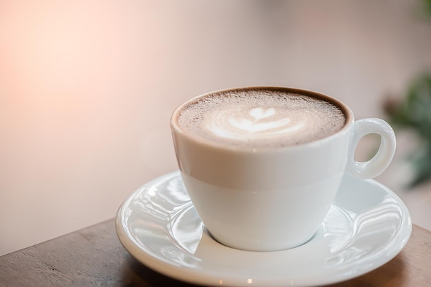 Foto taza de café con leche de arte o capuchino en la mesa de madera