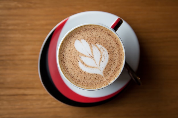 Taza de café con leche arte en piso de madera