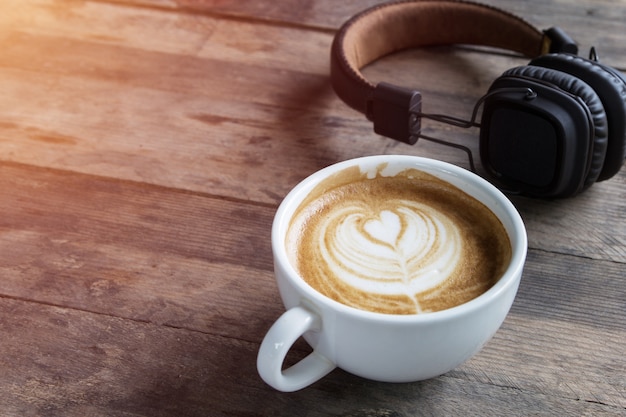 taza de café con leche y auriculares en la mesa