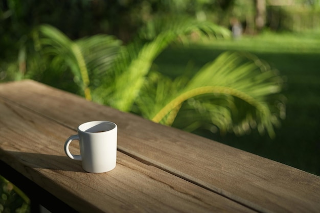 Taza de café con leche en un banco de madera marrón con fondo de hojas naturales
