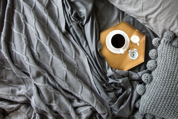 Taza de café con leche en una bandeja en la cama