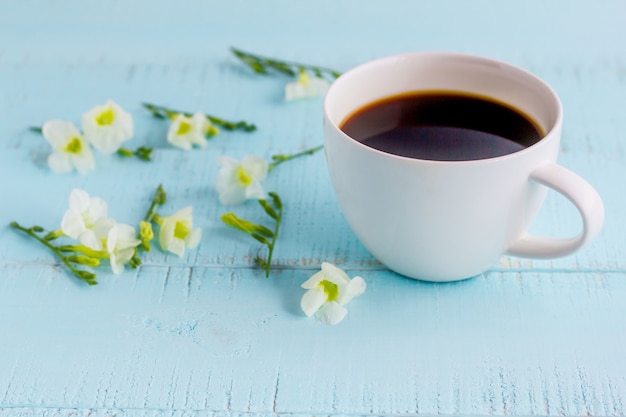 Taza del café con leche con café sólo y flores en la tabla de madera.