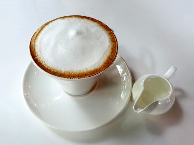 Una taza de café con leche caliente con almíbar sobre la mesa