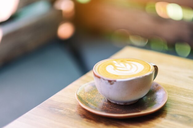 Una taza de café con leche caliente en la mesa de madera por la mañana