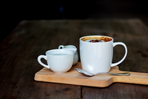 Taza de café con leche colocada sobre madera.