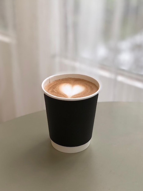 Taza de café con leche de corazón en la mesa