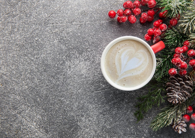 Taza de café con leche y decoración navideña sobre un fondo de hormigón oscuro