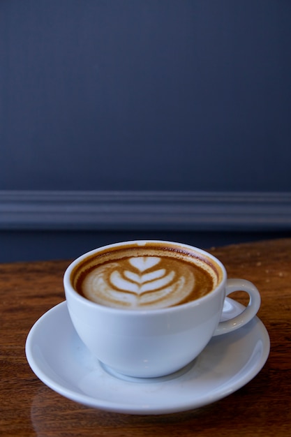 Taza de café con leche en el escritorio de madera