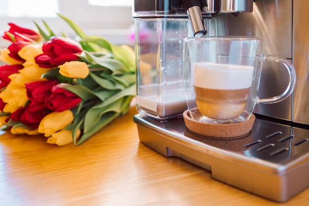 Taza de café con leche y flores de tulipanes en