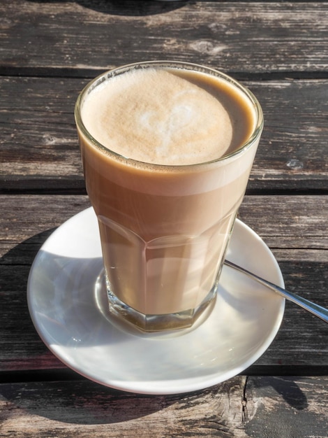 Taza de café con leche con forma de corazón en la mesa de madera