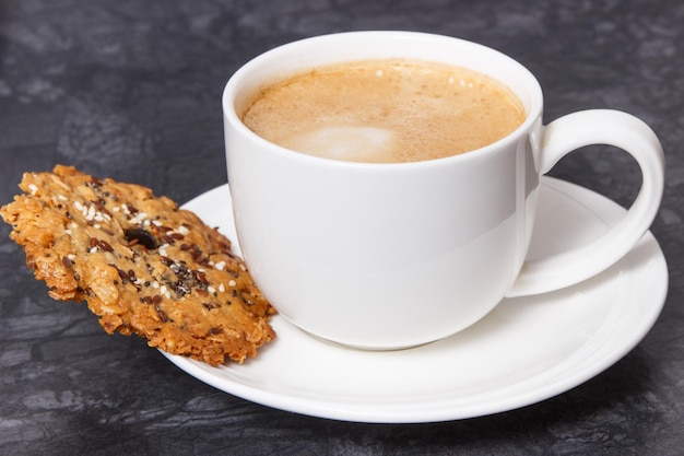 Taza de café con leche y galletas de avena recién horneadas con miel y semillas saludables Delicioso postre crujiente