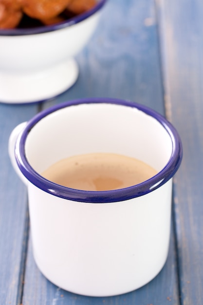 Taza de café con leche y galletas en madera azul