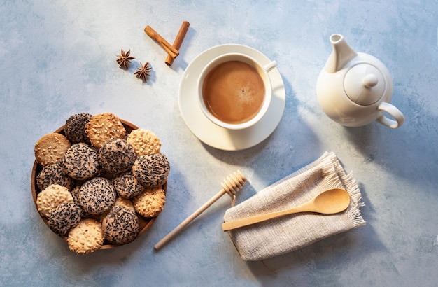 Taza de café con leche y galletas sobre fondo azul, vista alta